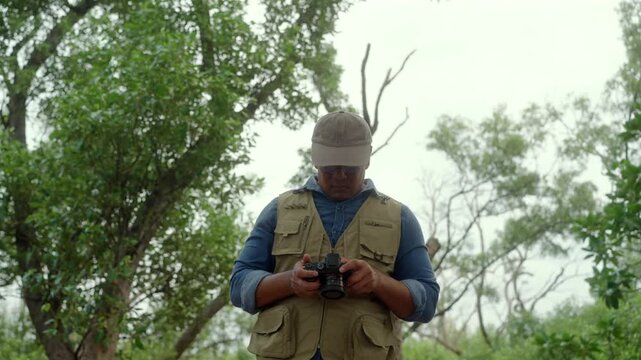 Happy active senior man walking through a forest taking photos of nature after retirement. Active aging outdoor recreation, healthy longevity, retirement lifestyle. Life insurance. Joyful living.
