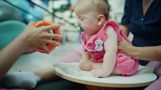 Infant receiving physical therapy treatment, developing motor skills, and engaging with a sensory toy during a hospital visit