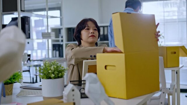 Asian employee and team packing personal belongings into box after job layoff,representing unemployed worker replaced by artificial intelligence,AI disruption business by AI automation technology