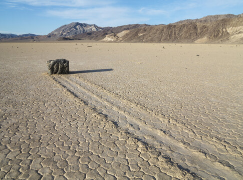 View of a sailing stone with a long trail on the cracked mud surface of Racetrack Playa in Death Valley, California, United States.