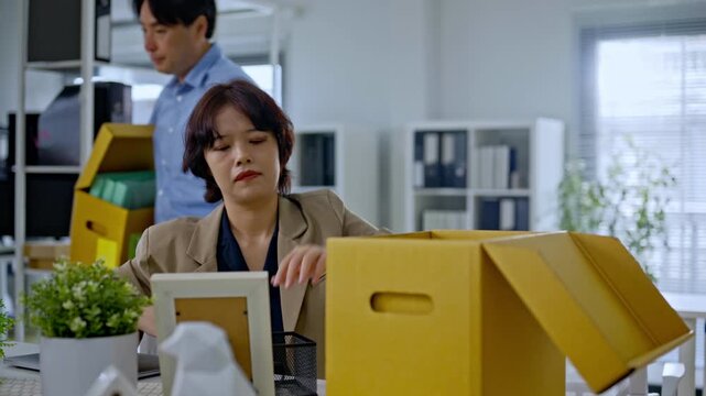Asian employee and team packing personal belongings into box after job layoff,representing unemployed worker replaced by artificial intelligence,AI disruption business by AI automation technology