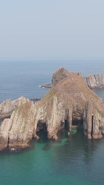 Vertical 9:16 aerial footage showcasing the striking rock formations and rugged cliffs of El Peine del Mar on the coast near Cudillero, Asturias, Spain.