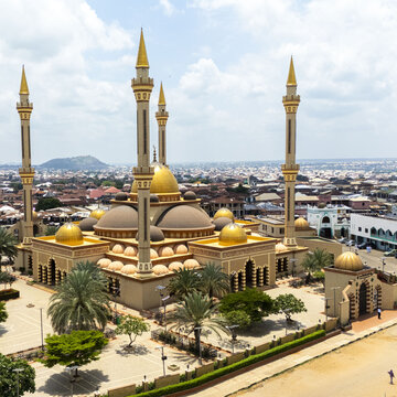 Aerial view of Ilorin Central Mosque with its golden domes and towering minarets surrounded by palm trees and the urban landscape of Oko Erin, Kwara, Nigeria.