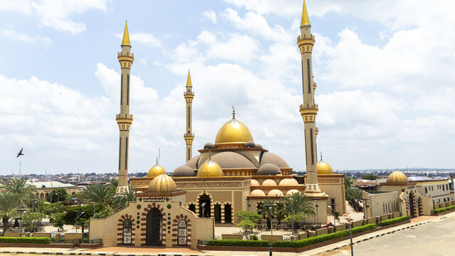 Aerial view of Ilorin Central Mosque with its golden domes and tall minarets, surrounded by lush green trees and paved courtyards in Oko Erin, Kwara, Nigeria.
