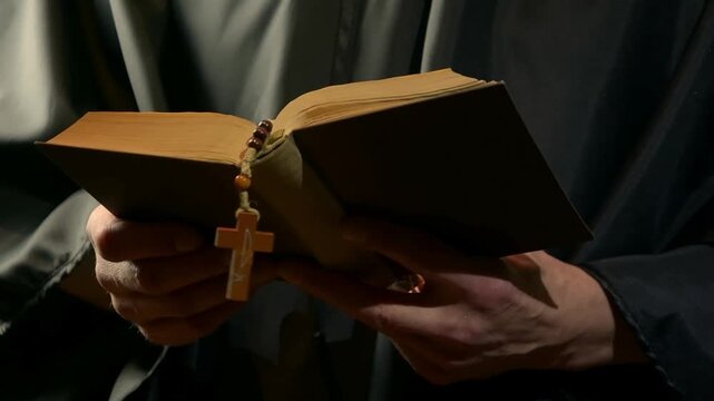 Monk reads from open prayer book and gestures during devotion