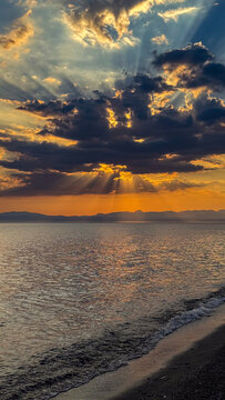 Dramatic sun rays through clouds over the sea at sunset