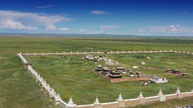 Aerial view of Erdene Zuu Monastery with its ancient white stupa wall and traditional temple buildings set in the vast green Mongolian steppe in Kharkhorin, Ovorkhangai, Mongolia.