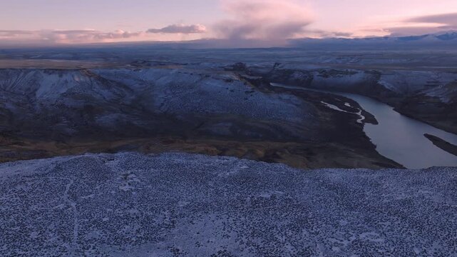 Aerial view of the snowy Morley Nelson Snake River Birds of Prey National Conservation Area at sunset with the Snake River winding through the canyon in Murphy, Idaho, United States.