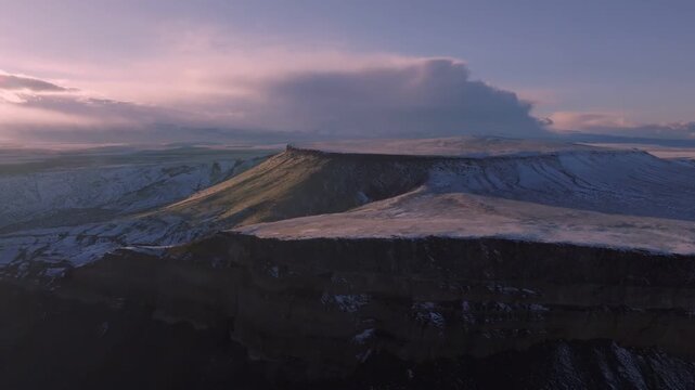 Aerial view of the Morley Nelson Snake River Birds of Prey National Conservation Area with snow-covered plateaus and dramatic sunset light in Murphy, Idaho, United States.