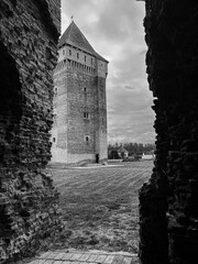 Castle tower framed by ancient stone walls, a medieval fortress scene with dramatic architecture, historical landscape, and cloudy sky over courtyard © Alexander