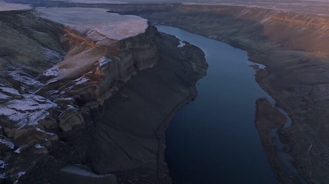 Aerial view of the Snake River winding through the Morley Nelson Snake River Birds of Prey National Conservation Area with rocky cliffs and light snow in Murphy, Idaho, United States.