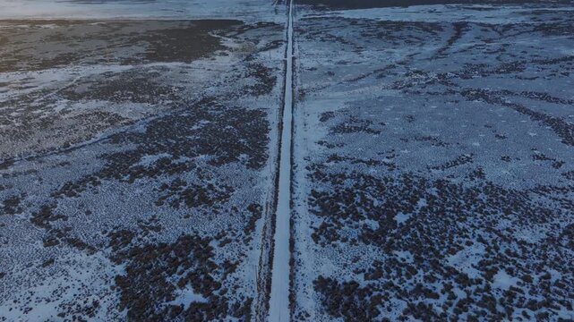 Aerial view of a straight road cutting through the snowy landscape of the Morley Nelson Snake River Birds of Prey National Conservation Area in Murphy, Idaho, United States.