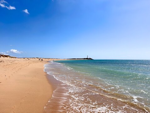 view from the wide sandy beach Playa de las Plumas to the lighthouse Faro de Trafalgar at the Atlantic Ocean, Costa de la Luz, Andalusia, Spain