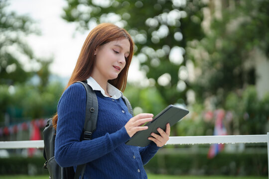 University student using a digital tablet outdoors on campus, reflecting mobile learning, academic lifestyle, and modern education with connected technology.