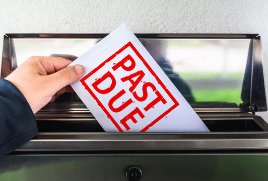 Hand Putting a Past Due Envelope into a Mailbox