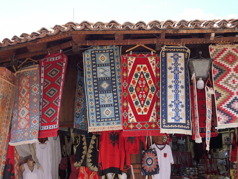 View of traditional hand-woven Albanian rugs and textiles displayed in a market stall in the historic Old Bazaar of Kruje, Durres County, Albania.