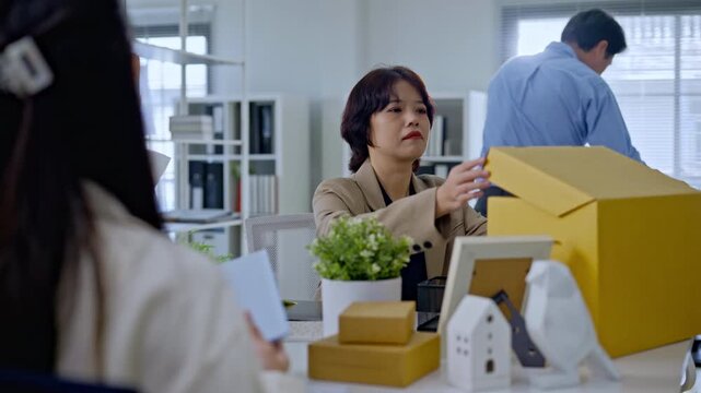 Asian employee and team packing personal belongings into box after job layoff,representing unemployed worker replaced by artificial intelligence,AI disruption business by AI automation technology