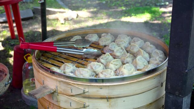 Steam rises from hot manti, a traditional Asian dish. Close-up of the steaming dumplings.