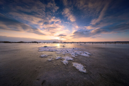 Golden Sunset Over Frozen Winter Field with Clouds
