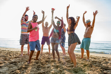 Obraz premium Group of friends dancing joyfully on a sunny beach.