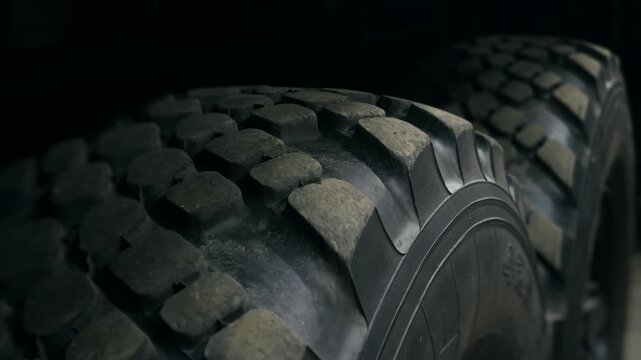 Close-up of heavy duty industrial vehicle tires with deep rugged tread. Durable rubber wheels designed for demanding work and rough terrain.