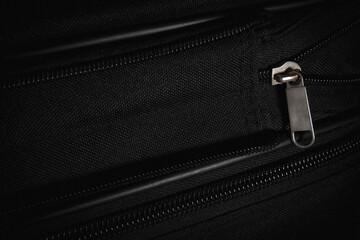 Macro view of a metal zipper on black textured fabric luggage. Concept of travel bags, packing for a journey, and secure suitcase fastening. © Win Nondakowit
