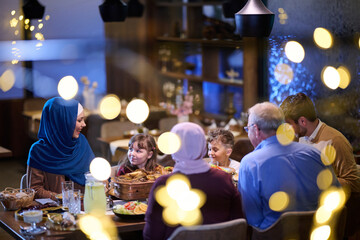 Fototapeta premium Multigenerational Muslim Family Enjoying Festive Dinner Together In Warm Restaurant Setting