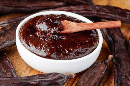 thick carob spread surrounded by dried carob pods