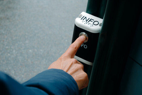 a man presses an outdoor public information button