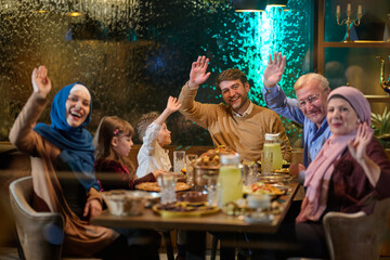 Fototapeta premium Multigenerational Muslim Family Waving During Festive Ramadan Iftar Dinner Together At Home