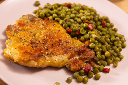 Delicious crispy chicken with peas as a side dish on a plate