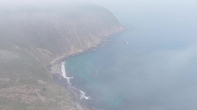 Aerial footage capturing the rugged rocky coastline of San Andres de Teixido, Spain. The overcast weather creates a moody and atmospheric coastal view. No people are visible in the frame.
