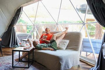 Fototapeta premium Cozy glamping lifestyle with a couple resting indoors in a modern geodesic dome surrounded by nature.