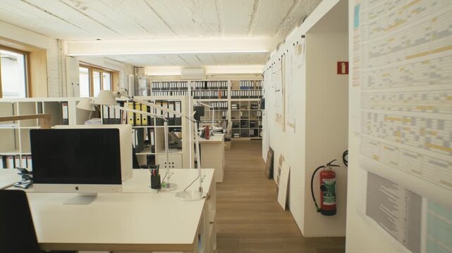 Empty design office with desks and shelves full of binders