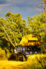 Camping setup with rooftop tent on vehicle in a natural setting © Voyagerix