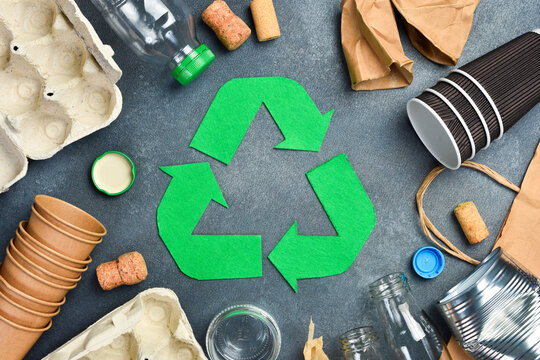 Recycling symbol and various garbage for recycling on gray concrete background. Eco concept.