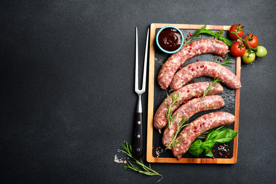 Meat fork and raw beef sausages ready for grilling. Top view. Homemade meat products.
