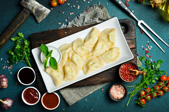 Traditional Ukrainian dumplings with salty cheese and potatoes. On a black stone background.
