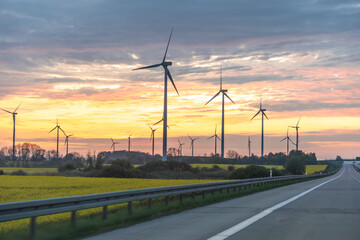 Fototapeta premium Wind turbines near rural highway. Renewable energy and infrastructure content.