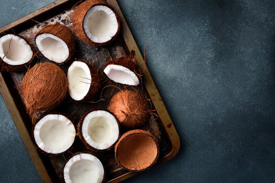 Fresh open coconuts on a metal tray. Tropical nuts close-up. On a dark background.