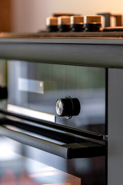 Black built-in oven with control knob. Modern kitchen appliance detail.