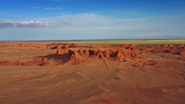 Aerial view of the iconic red sandstone Flaming Cliffs landscape in the Gobi Desert, featuring vast arid terrain under a clear blue sky in Bulgan, Omnogovi, Mongolia.
