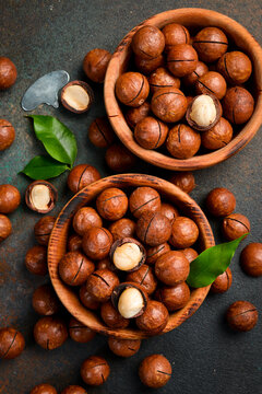 Wooden bowl filled with macadamia nuts. Roasted delicious nuts. Top view.