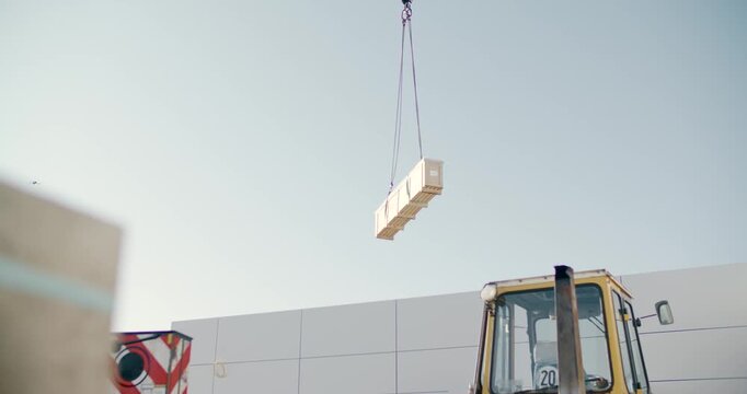 Crane lifting a prefabricated wall element above a building site