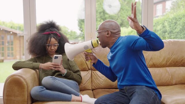 The girl staring at phone without taking her eyes off it, while her father is trying to call her using megaphone. The father is shouting at her daughter, but she isn&rsquo;t paying any attention.