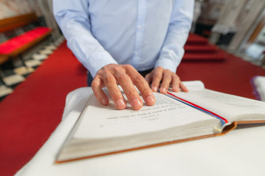 A man reads from a bible at a lectern during Holy Mass in a European Catholic church. He shows his faith and devotion.