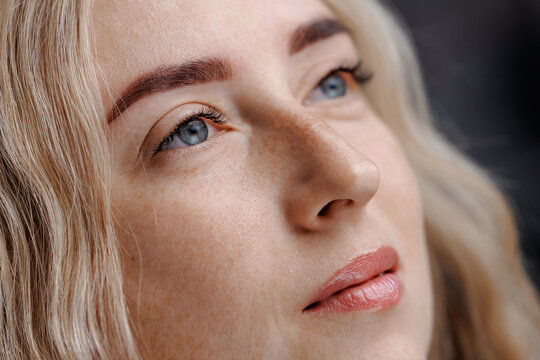Young woman gazing upward in studio portrait closeup after permanent