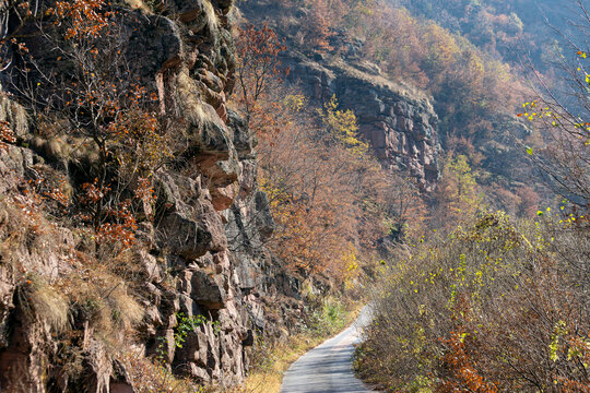View of a narrow road winding through a rocky canyon with autumn foliage and steep cliffs in Topli Do, Pirot District, Serbia.