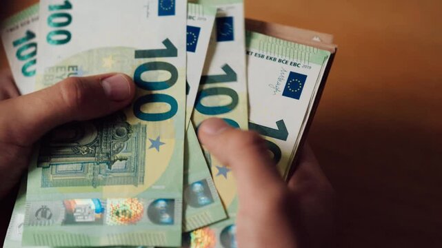 Counting and handling euro banknotes.