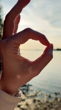 Hand Framing the Setting Sun Over a Lake Vertical Video